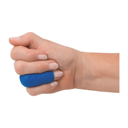 A hand with a blue BeeSana© SafeCut finger bandage from Meditrade GmbH envelops the thumb for wound protection. The light-skinned fist is slightly closed, with the thumb extended outward, against a plain white background.