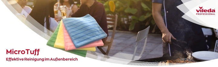 Werbung für Vileda Professional MicroTuff – farbige Reinigungstücher in Blau, Gelb, Rosa und Grün. Im Hintergrund eine Szene im Außenbereich mit Menschen, die an einem Tisch sitzen, und einer Person, die an einem Grill arbeitet. Text: 'MicroTuff – Effektive Reinigung im Außenbereich'.