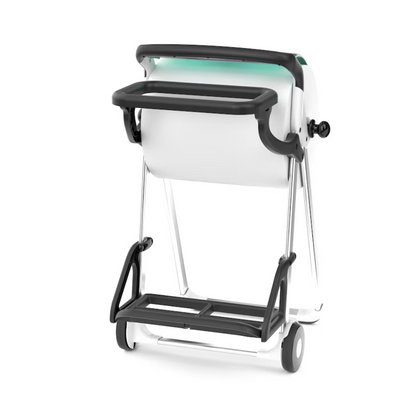 A Tork 206550 trash bag holder for floor stands in white and black, with wheels, a handle, and a centrally positioned paper or fabric roll. The metallic structure resembles a floor stand and shows the Tork trash bag holder from a slightly inclined perspective.