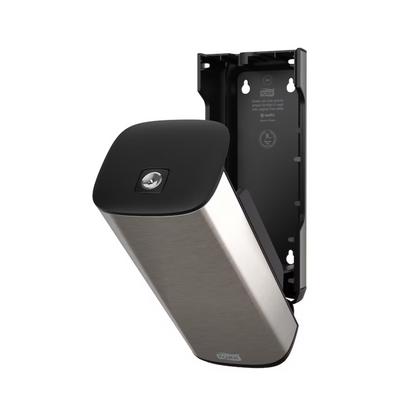 A Tork 460010 dispenser for soap and hand sanitizers in stainless steel and black from Essity Professional Hygiene Germany GmbH for wall mounting with an open front panel that reveals the interior compartment. This modern design also features a partially detached plate that exposes the interior bracket and screw positions.