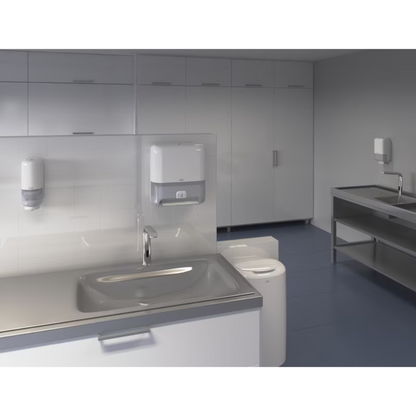 The laboratory impresses with a modern and clear aesthetic with white cabinets and a stainless steel sink. Next to paper towel dispensers, a wall-mounted Tork Matic® 551100 sensor dispenser for roll towels Elevation H1 by TORK – Essity Professional Hygiene Germany GmbH can be seen. The design of the room is minimalist, with blue flooring and ample storage space.