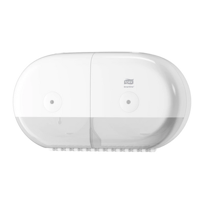 On the wall is a Tork SmartOne® 682000 Mini Twin Roll Dispenser, manufactured by TORK – Essity Professional Hygiene Germany GmbH. This white, oval dispenser features a transparent lower part and is specifically designed with its smooth, modern look to accommodate twin rolls of toilet paper.