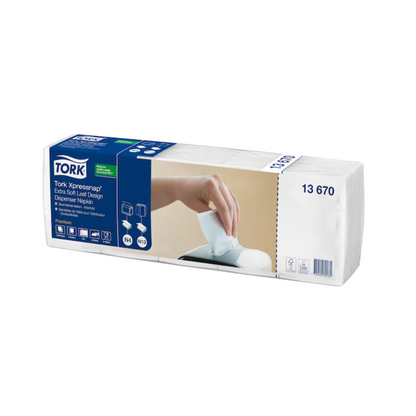 A box of Tork Xpressnap® 13670 Extra Soft leaf design white dispenser napkin Premium N4 2-ply, manufactured by TORK – Essity Professional Hygiene Germany GmbH, contains eight packs. The packaging illustration shows a hand pulling a napkin from the dispenser, highlighting the extra soft texture of these white napkins.