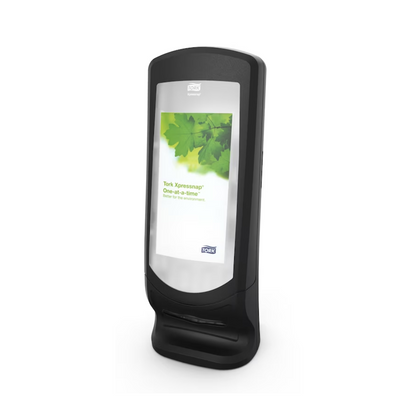 A Tork Xpressnap® 272211 Stand and Wall Dispenser N4 with a leaf design on the front label. This dispenser is manufactured by TORK – Essity Professional Hygiene Germany GmbH and is designed for dispensing single napkins, thereby improving hygiene in any environment.