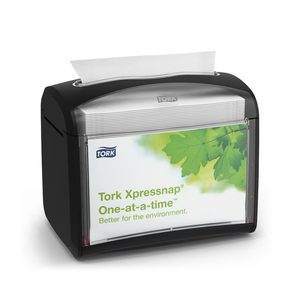 A black Tork Xpressnap® 272611 table napkin dispenser, distributed by TORK – Essity Professional Hygiene Germany GmbH, is presented with a label featuring green leaves and the message "Individually. Better for the environment." A single napkin is partially dispensed from the top to promote hygiene and efficient napkin use.