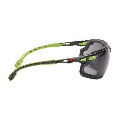 Eine 3M™ Solus™ Schutzbrille 1000 von 3M Deutschland GmbH in grün/schwarz mit Scotchgard™ Antibeschlag-Beschichtung, abnehmbarer Schaumstoffdichtung und grauen Gläsern in der Seitenansicht auf weißem Hintergrund.