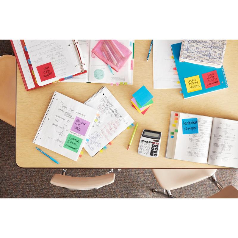Top view of a classroom table with open notebooks, calculator, pens, school books, PEFC-certified folders, and 3M Post-it® Notes Energetic Collection (76 mm x 127 mm, 100 sheets/block, 6 blocks/pack). Three chairs are around the table.
