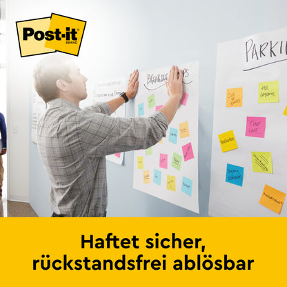 Ein Mann klebt bunte Post-it® Zettel auf eine Post-it® Super Sticky selbsthaftendes Recycling Meeting Chart 559RP (63,5 x 76,2 cm, 30 Blatt/Block, 2 Blöcke/Packung) von 3M Deutschland GmbH, unten mit "Haftet sicher, rückstandsfrei ablösbar".