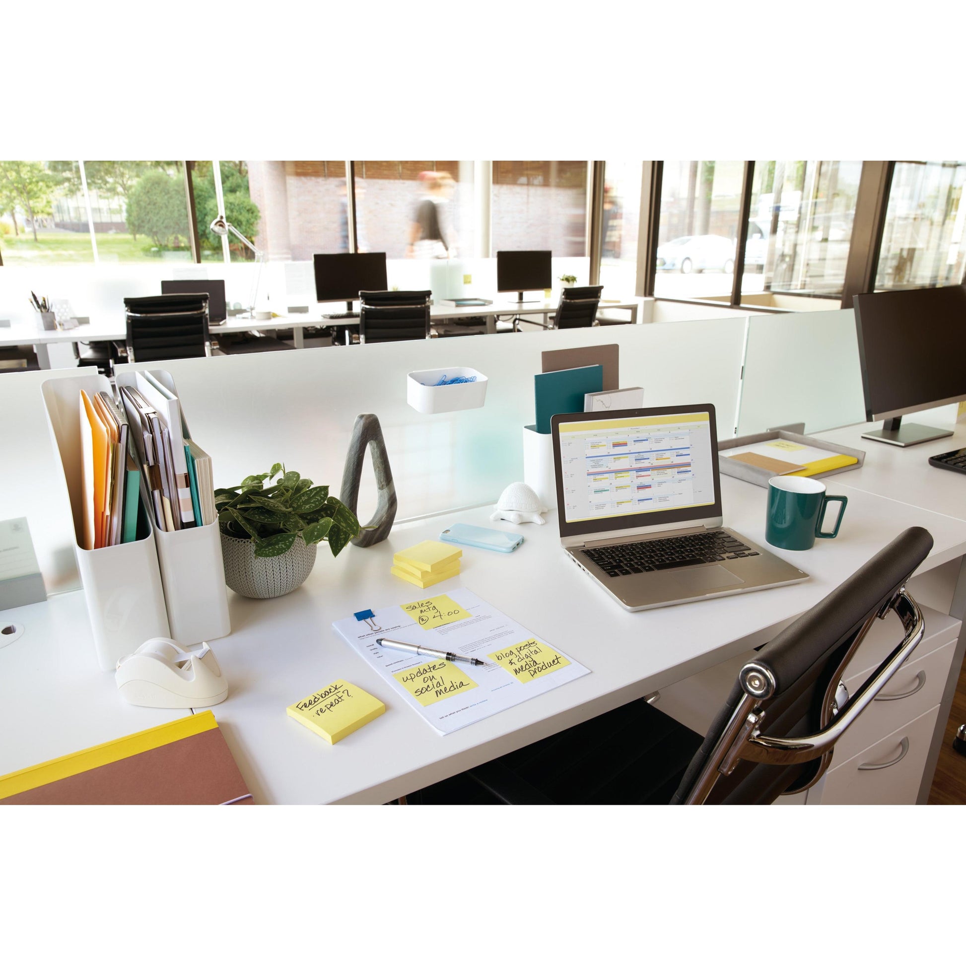 Ein helles Büro mit Laptop, Papierkram, Stiften, Tasse, einer Pflanze und den Post-it® Notes (Gelb, 76x76mm), Promotion Pack (16+4 gratis), PEFC-zertifiziert von 3M Deutschland GmbH auf dem weißen Schreibtisch. Fenster bieten einen Ausblick.