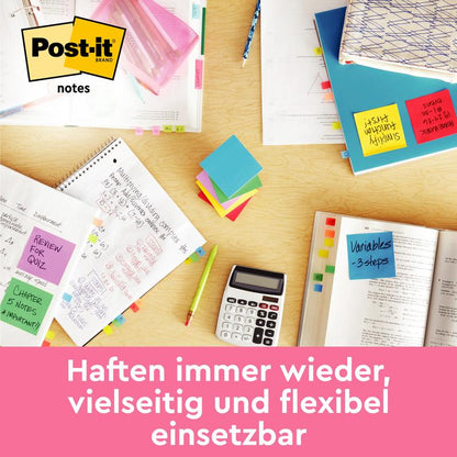 A desk with open notebooks, calculator, pen, highlighter, and scattered 3M Deutschland GmbH Post-it® Notes from the Energetic Collection (76 x 127 mm, 100 sheets/block, 6 blocks/pack, 100% PEFC). Stick repeatedly, versatile use.
