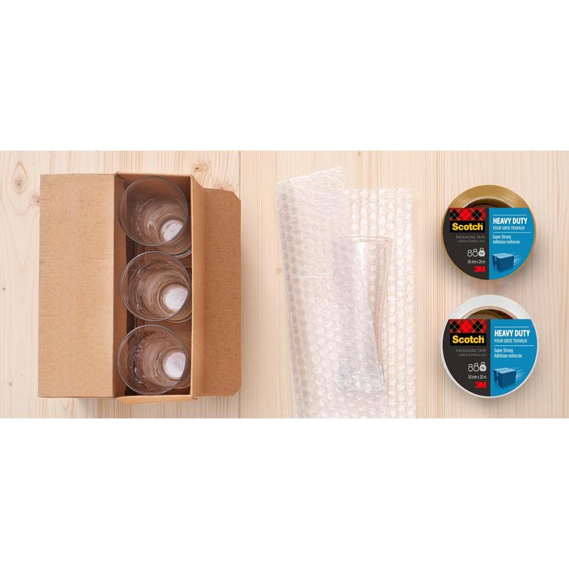An open box with four glass cups, bubble wrap, and a Scotch® Extra strong packaging tape (48 mm x 20.3 m) from 3M Deutschland GmbH stands on a light wood surface.