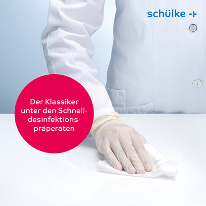 A person in a white lab coat and gloves cleans a surface with Schülke mikrozid® AF wipes disinfectant wipes. In a speech bubble, it says in German: “The classic among rapid disinfection preparations.” In the upper right corner is the company logo of Schülke & Mayr GmbH, emphasizing the commitment to rapid alcoholic disinfection.